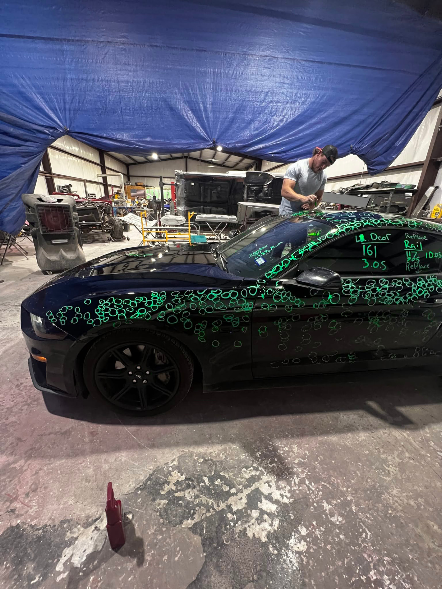Hail damage marked out on a black Mustang before repair